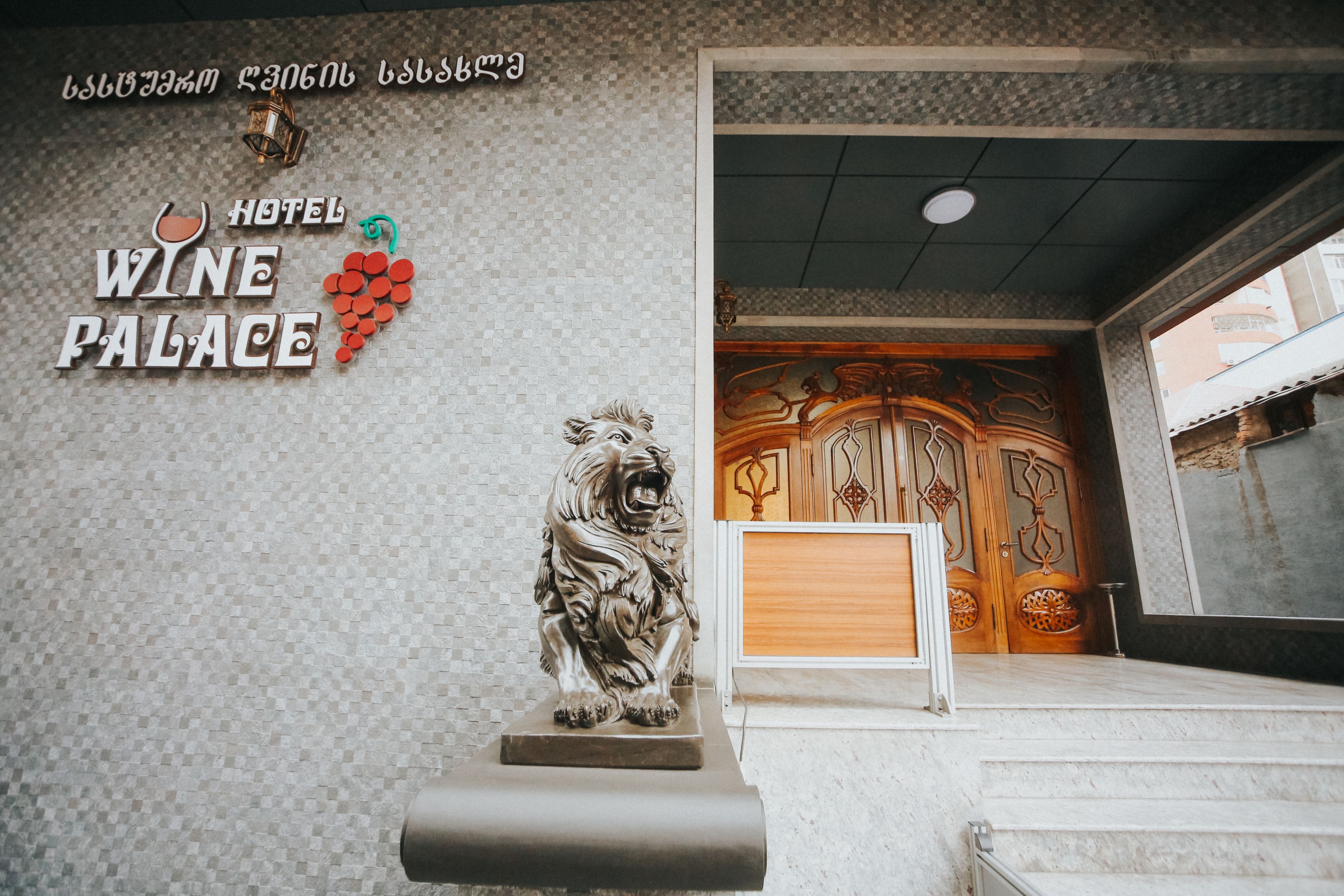 A hotel entrance with a sign reading "HOTEL WINE PALACE" and a lion statue.