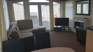 Una habitación con sofá, televisor, chimenea y mesa de comedor.