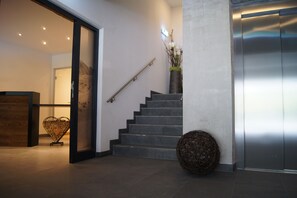 A modern interior with a staircase, a reception desk, and a decorative vase.