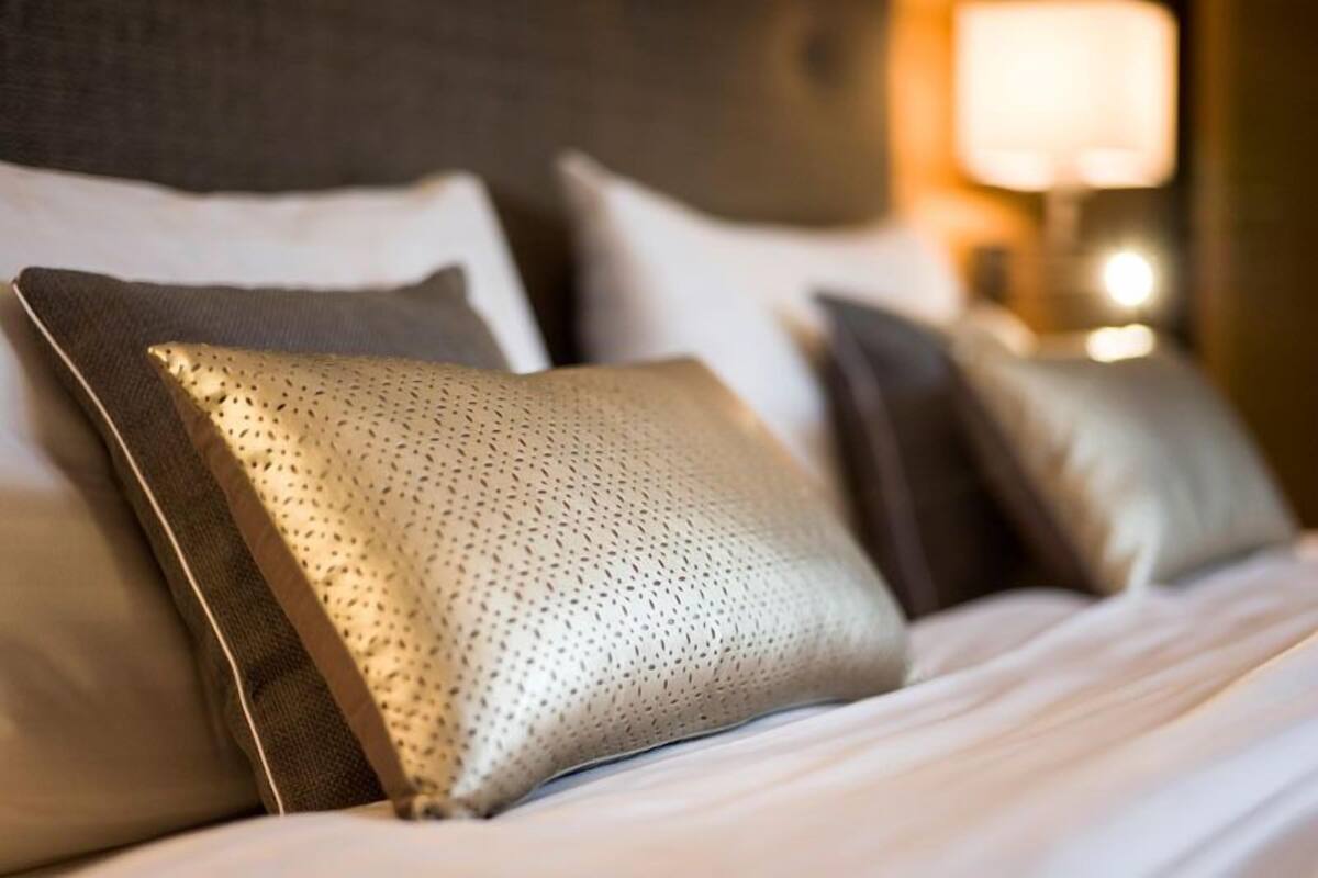 A neatly made bed with a patterned pillow and a plain pillow.