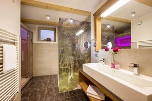 A modern bathroom with a large mirror, a white sink, and a shower with a glass door.