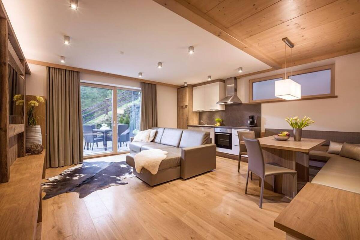 A modern living room with a sofa, a dining table, and a kitchen area.