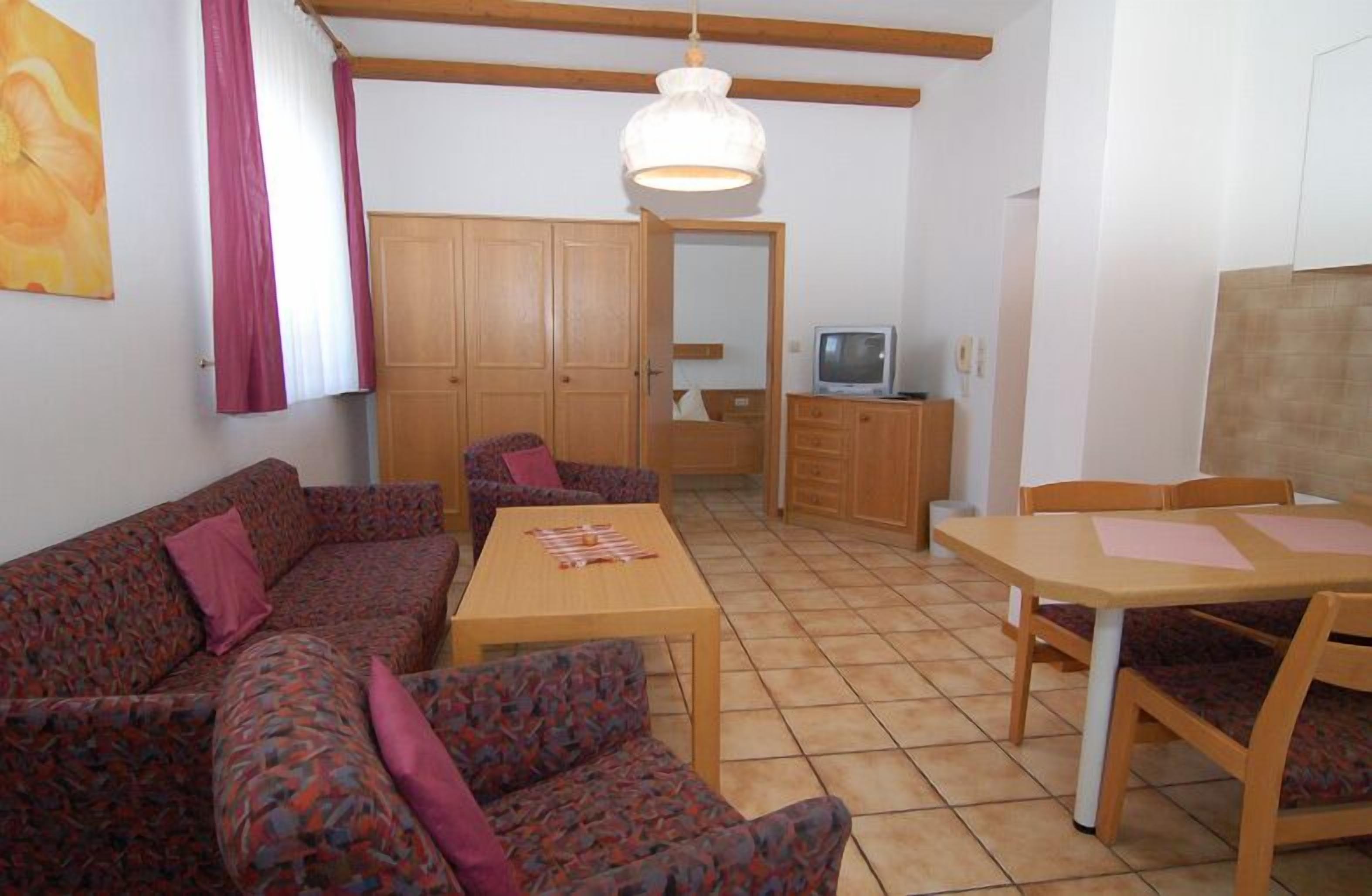A room with a sofa, a table, and a television.