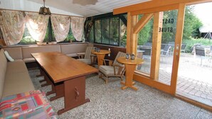 Une pièce chaleureuse avec une table en bois, des sièges confortables et une grande fenêtre avec des rideaux.