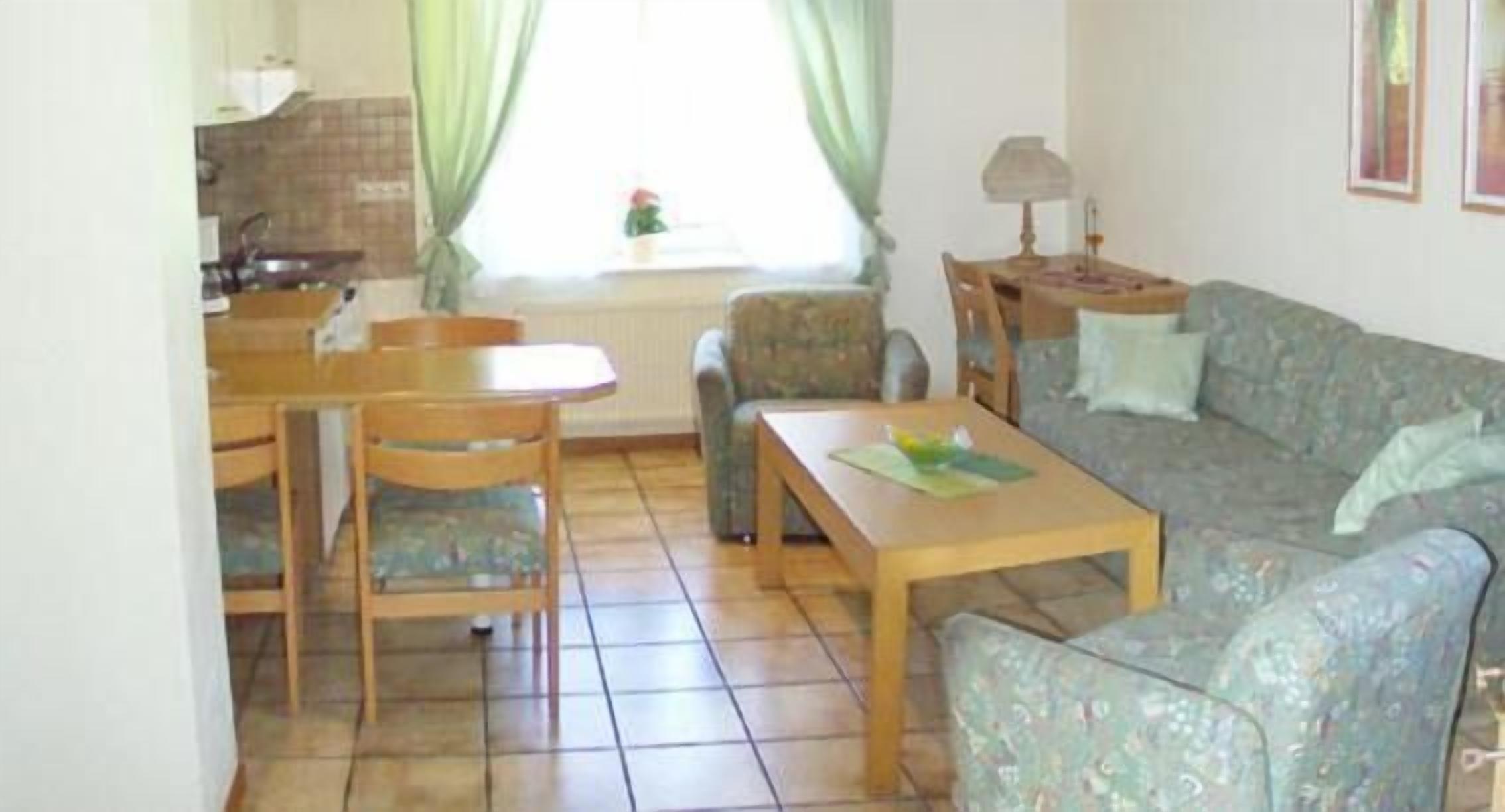 A living room with a sofa, a coffee table, and a dining area with chairs and a table.