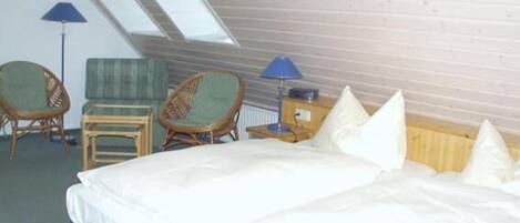 Een kamer met een bed, twee stoelen, een klein tafeltje en een lamp.