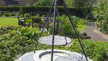 Un espacio de estar circular al aire libre con un columpio en un jardín ajardinado.