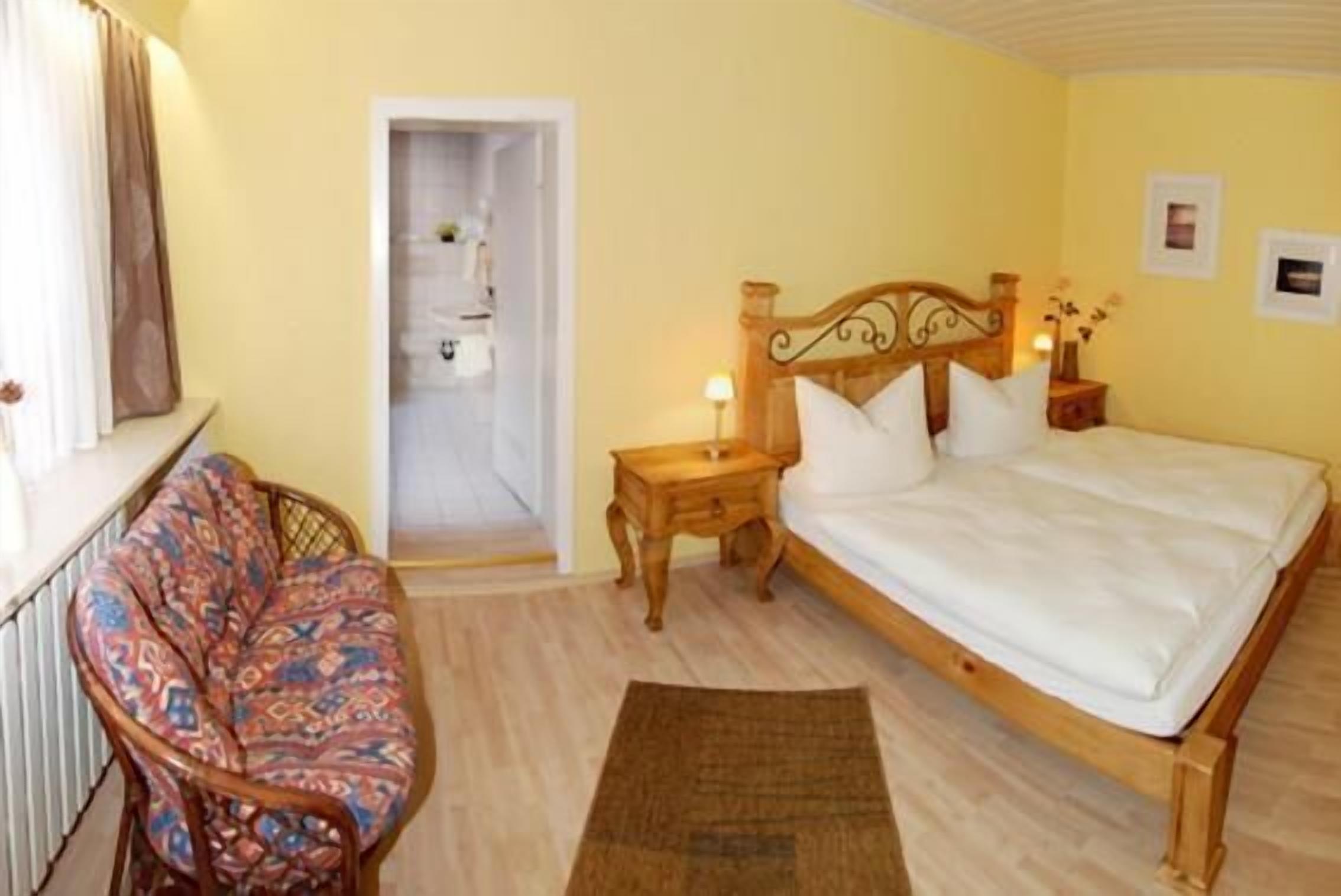 A bedroom with a wooden bed, a nightstand, a chair, and a small table.