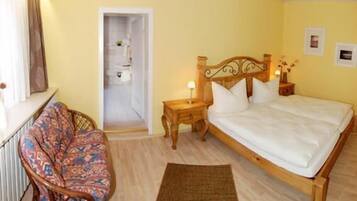 A bedroom with a wooden bed, a nightstand, a chair, and a small table.