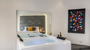 Une salle de bain moderne avec une grande baignoire, un miroir et une œuvre d’art abstraite aux couleurs vives accrochée au mur.