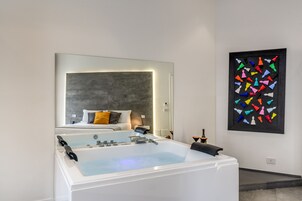 Un bagno moderno con una vasca da bagno ampia, uno specchio e un'opera d'arte astratta dai colori vivaci appesa al muro.