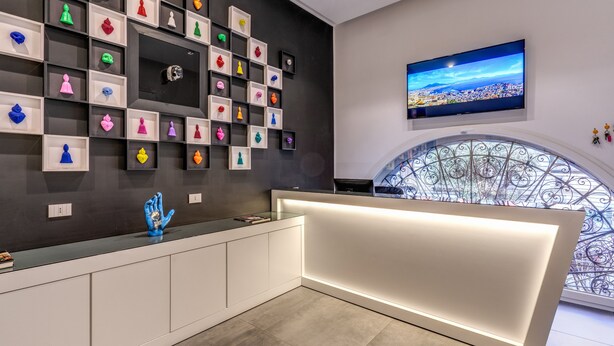 A reception area with a modern design, featuring a large TV on the wall and a decorative railing near a window. - Gallery Suite Naples (Naples)