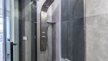 Une salle de bain moderne dotée d’une douche à parois de verre, de toilettes intégrées et d’un porte-serviettes apparent.