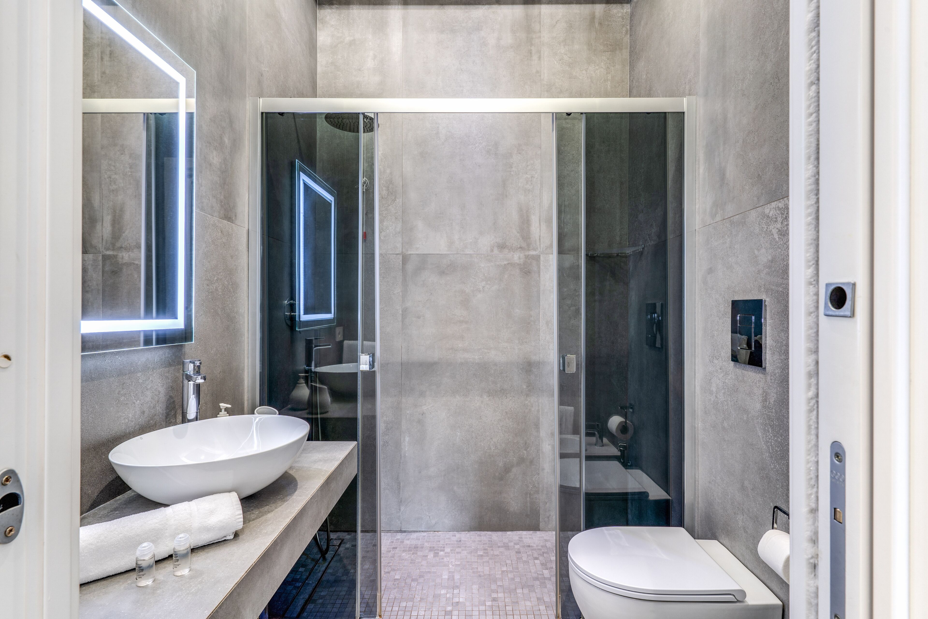 Un bagno moderno con un lavandino bianco grande, una cabina doccia in vetro e un water.
