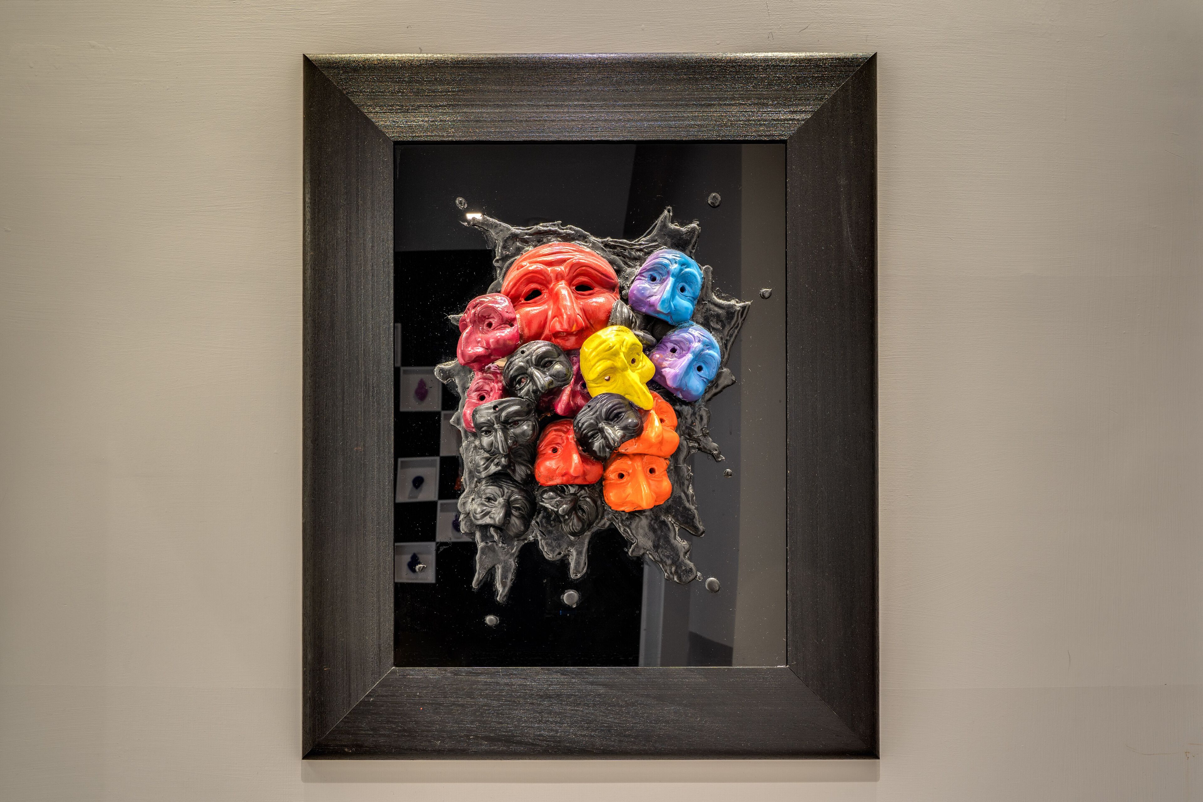 A framed artwork with abstract figures and splashes of color.