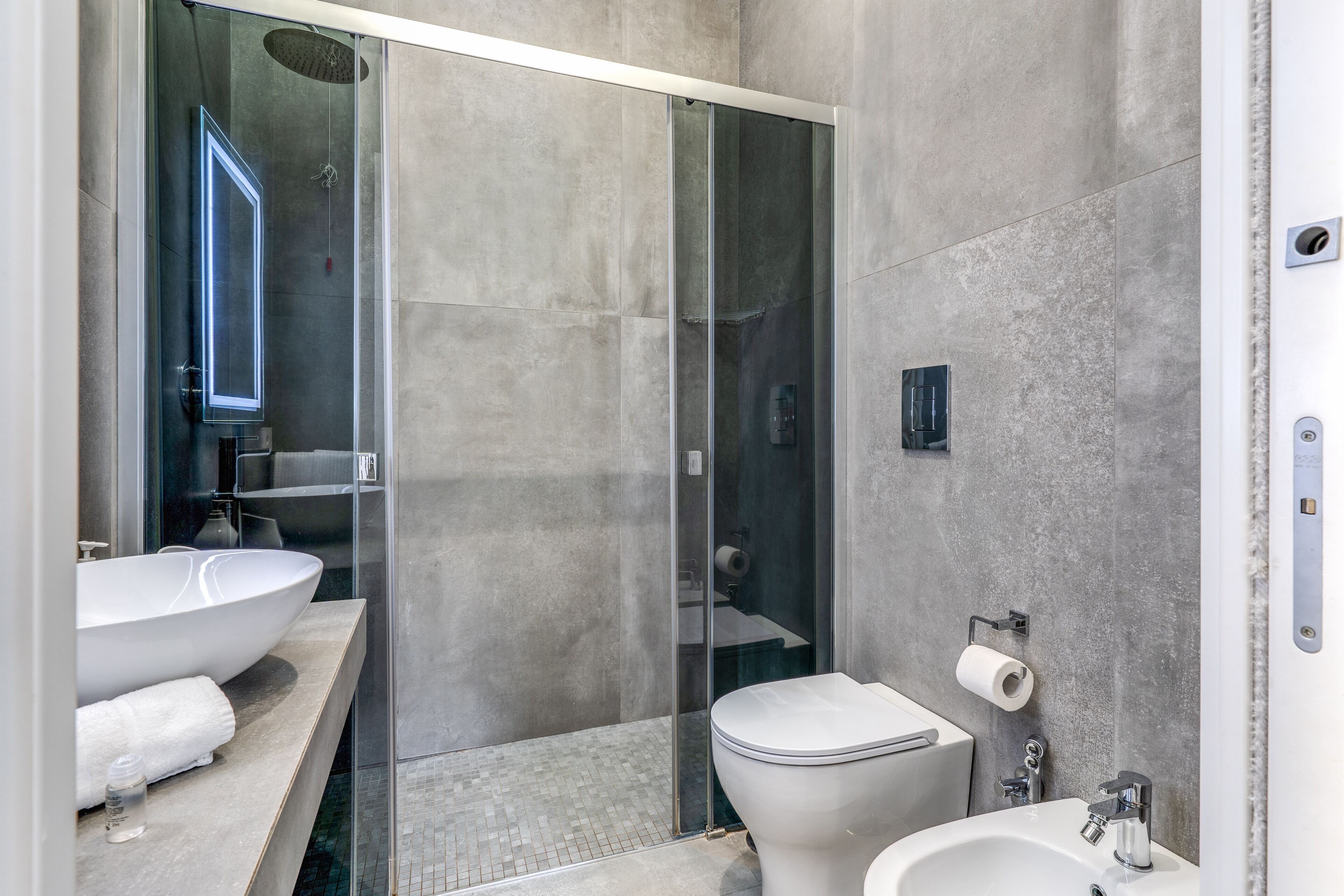 A modern bathroom with a glass-enclosed shower, a large white sink, and a toilet.