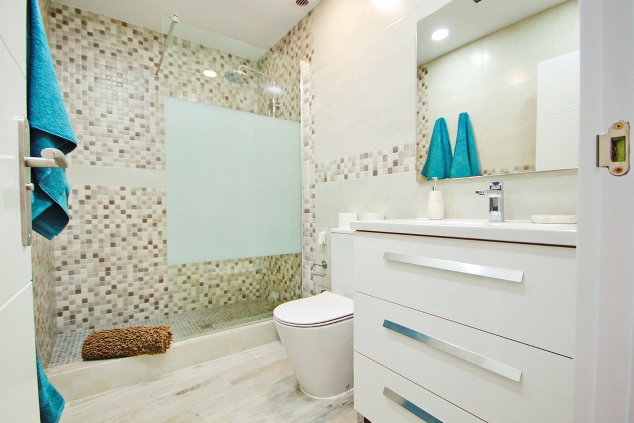 Un baño moderno con ducha, inodoro y tocador.