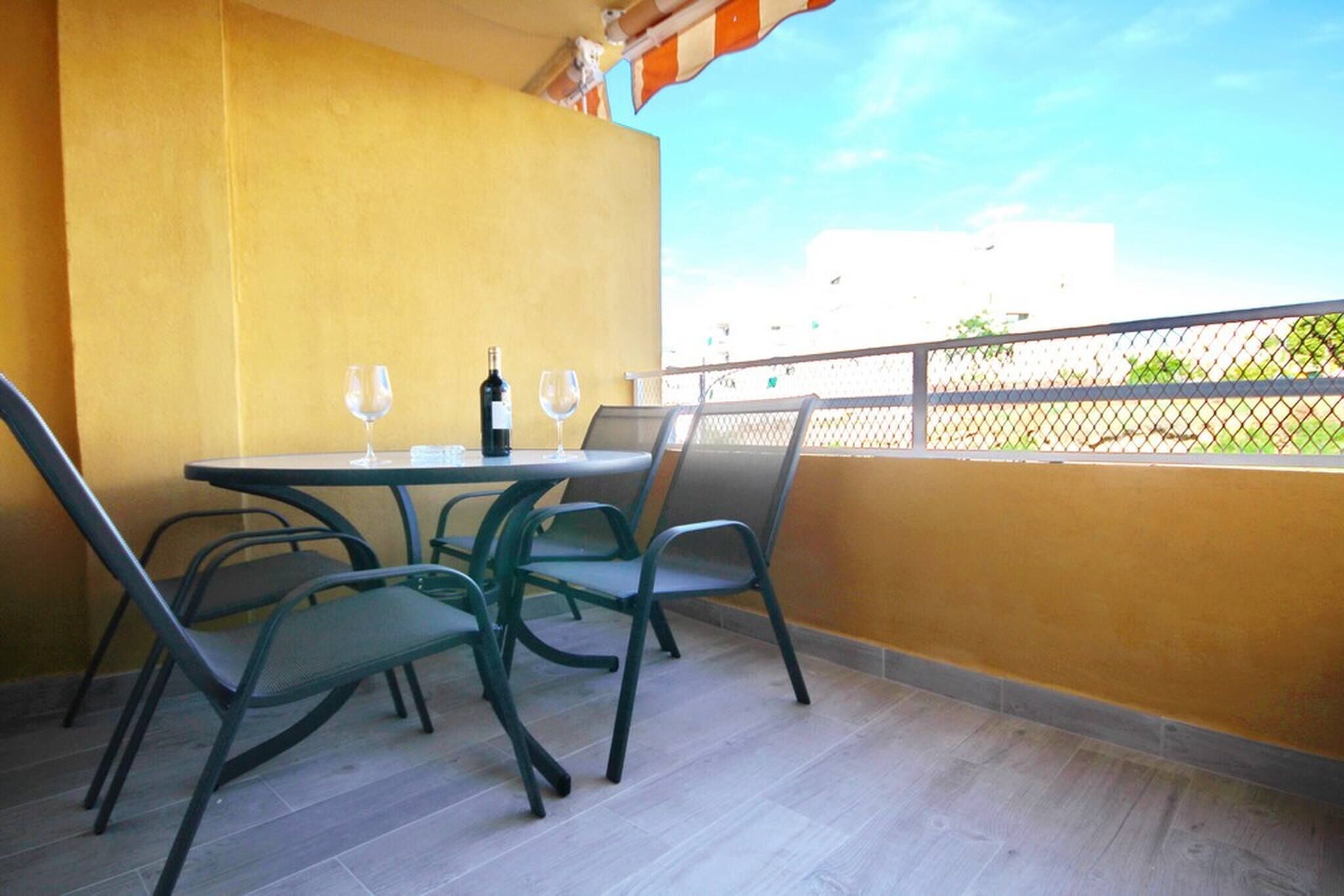A balcony with a table and chairs, a bottle of wine, and two wine glasses.