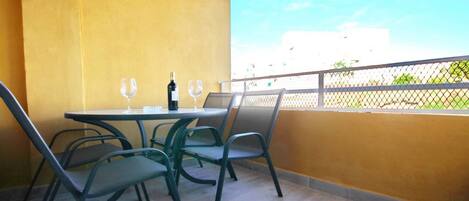 A balcony with a table and chairs, a bottle of wine, and two wine glasses.