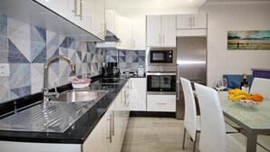 A modern kitchen with white cabinets, a black countertop, and a stainless steel sink. - Apartment with a pool in Costa Adeje (Adeje)