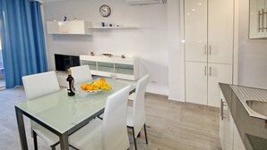 A modern kitchen with white cabinets, a glass dining table, and a clock on the wall. - Apartment with a pool in Costa Adeje (Adeje)