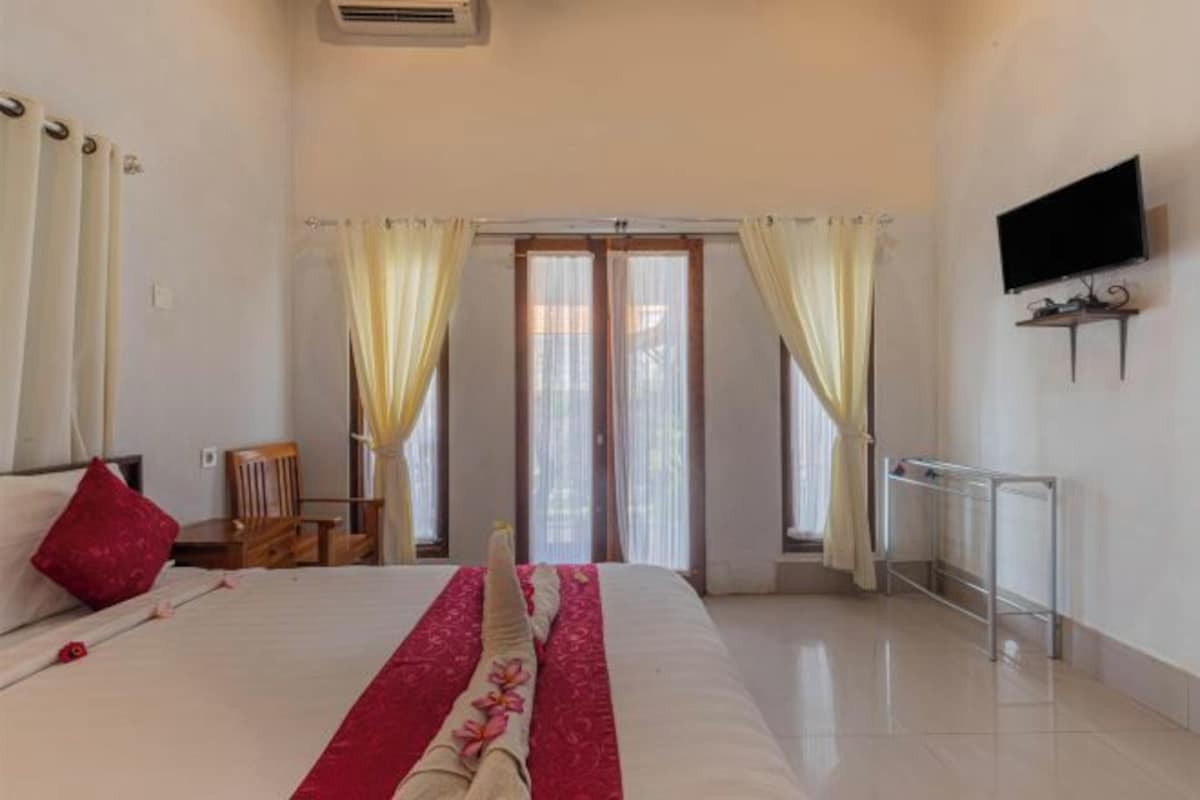 A hotel room with a bed, curtains, a TV, and a window.