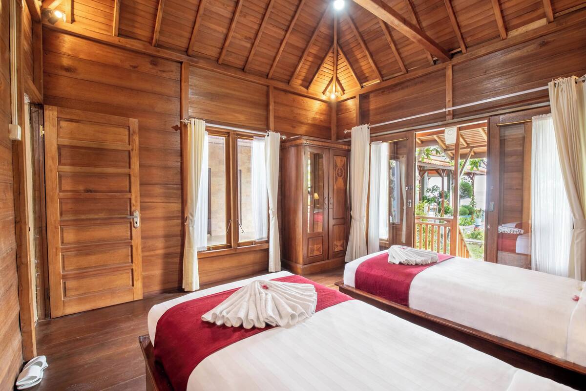 A wooden cabin room with two beds, a wardrobe, and a balcony.