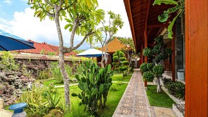 A courtyard with a patterned walkway, various plants, and traditional architecture. - Swan Beach Inn (Penida Island)