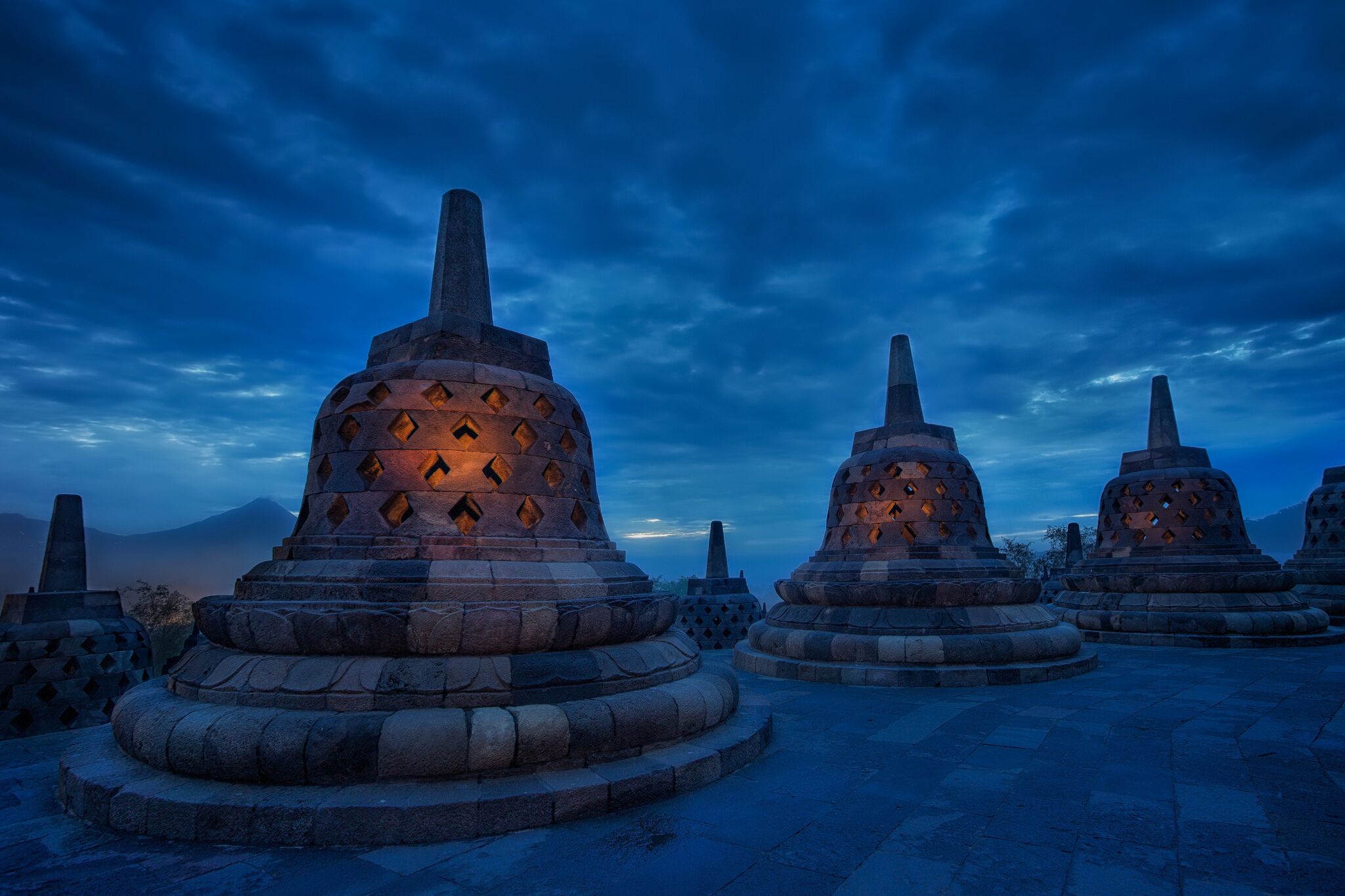 Stone stupas with a tiered design, arranged in a circular pattern on a paved area.