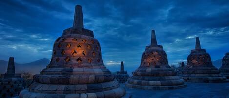 Stone stupas with a tiered design, arranged in a circular pattern on a paved area.