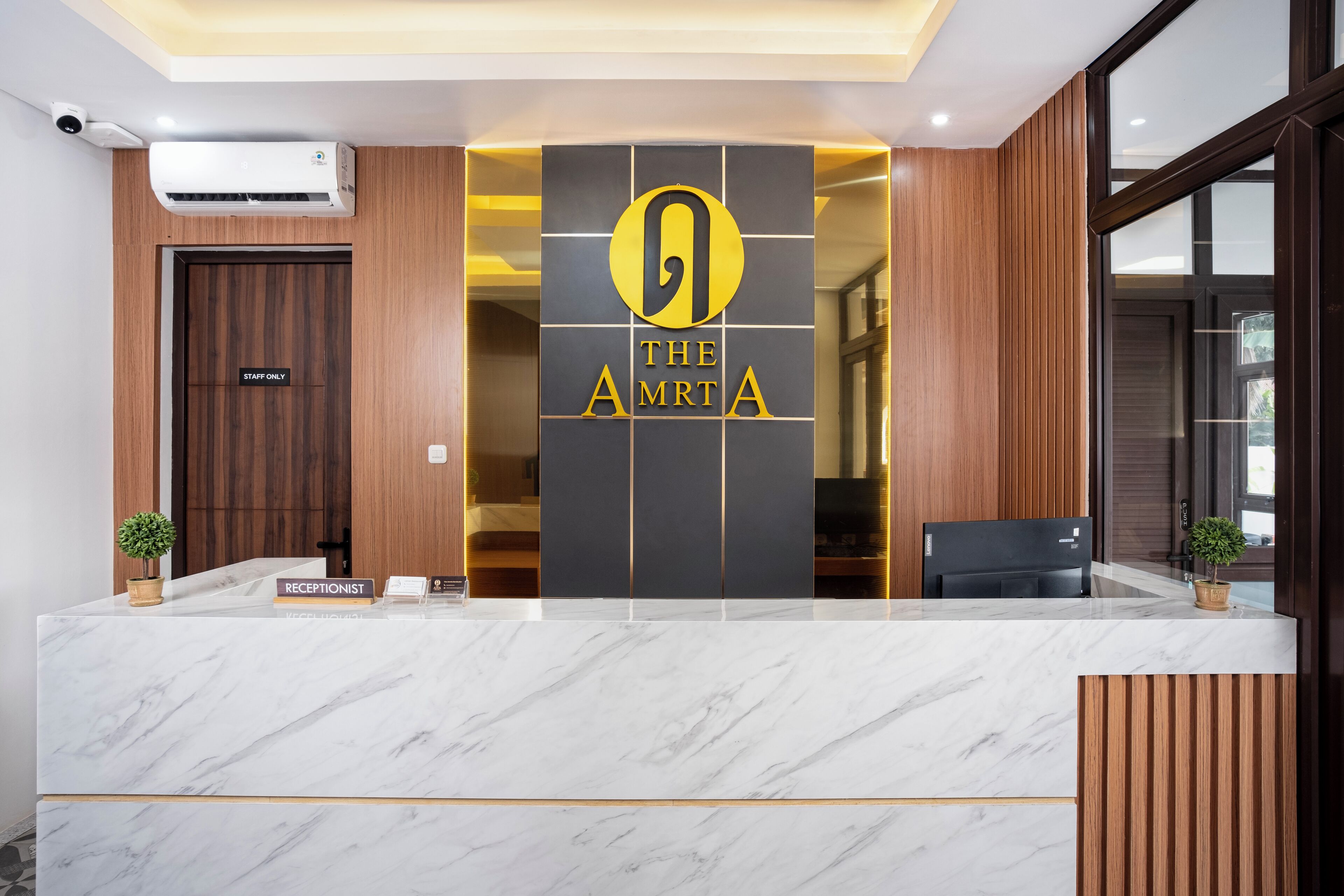 A reception desk with a marble top, a "STAFF ONLY" door, and a logo for "THE AMRTA".