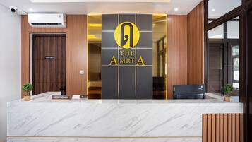 A reception desk with a marble top, a "STAFF ONLY" door, and a logo for "THE AMRTA".