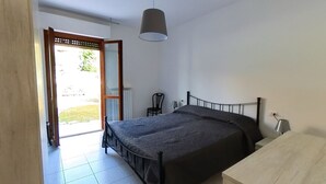 A bedroom with a bed, a desk, a chair, a hanging lamp, and a door leading outside. - S044 - Sirolo, delightful three-room apartment with garden (Sirolo)