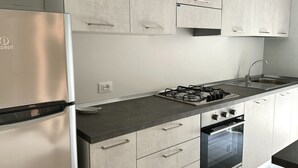 A modern kitchen with a stainless steel refrigerator, a gas stove, a sink, and a built-in oven. - S044 - Sirolo, delightful three-room apartment with garden (Sirolo)