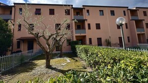 A multi-story residential building with balconies, a paved courtyard, and a street lamp. - S044 - Sirolo, delightful three-room apartment with garden (Sirolo)