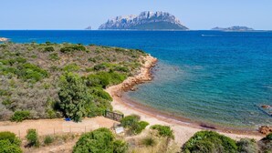 A coastal landscape with a rocky beach, clear blue sea, and a distant island. - Villa Gaviel, private descent to lonely beach, scenic P. Istana, wifi (Porto Istana, Olbia)