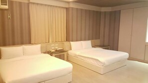 A hotel room with two beds, a bedside table with a lamp, and a large window with curtains. - Wind Coast Motel (Hsinchu)