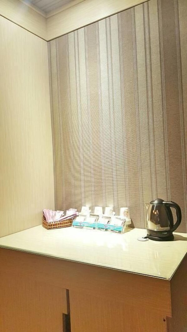 Pequeña cocina americana con una encimera, un hervidor y una cesta de objetos.