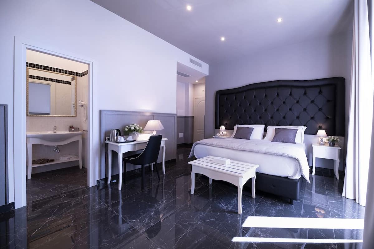 A modern bedroom with a large bed, a desk, and a vanity.