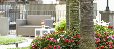 A garden with a palm tree, a bench, and a table with flowers.