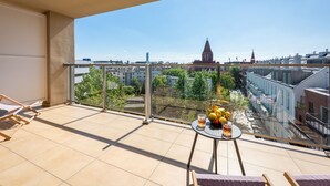 A balcony with a table set for two, a chair, and a view of the cityscape.
