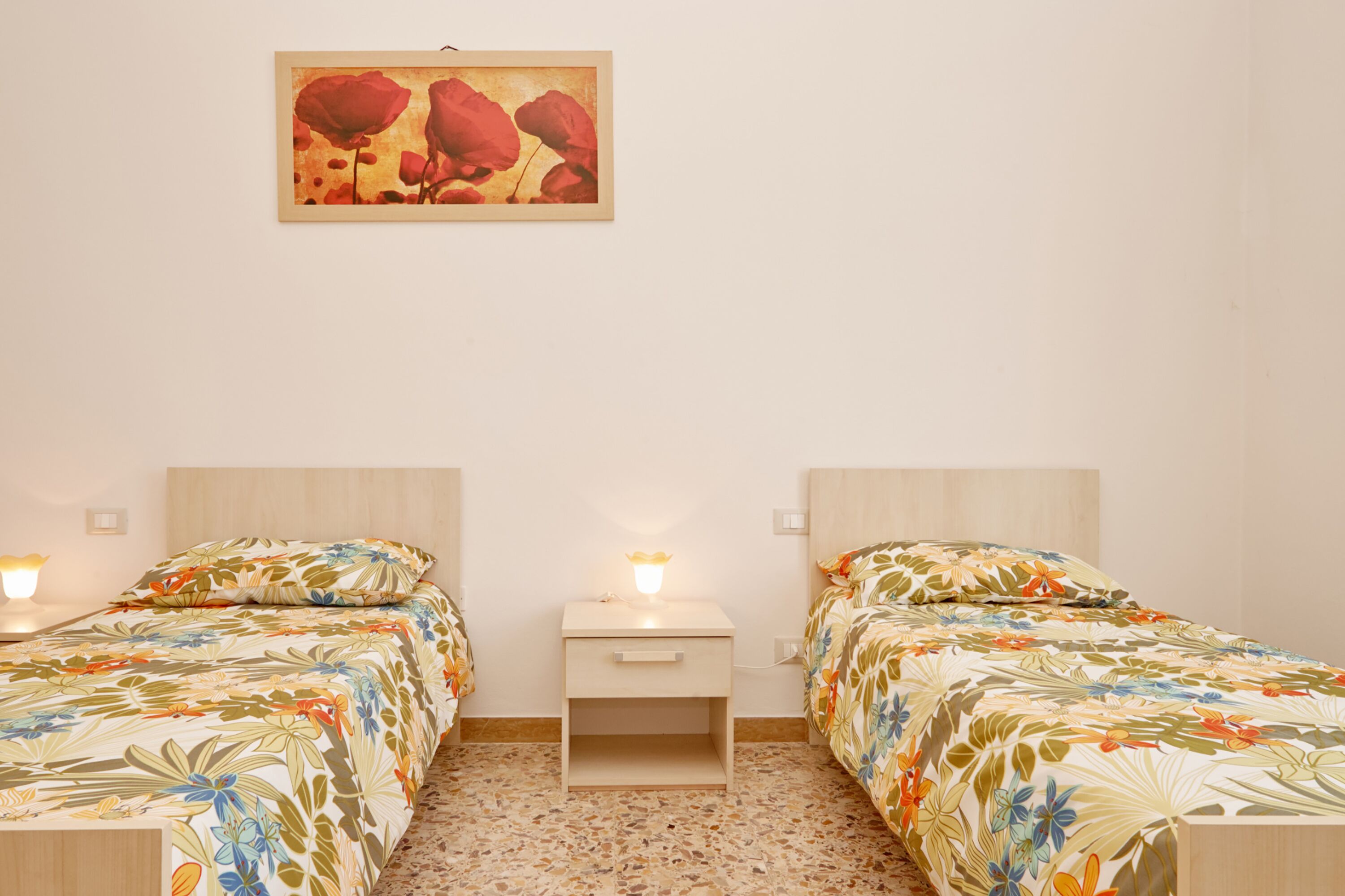 Un dormitorio con dos camas, una mesita de noche y un cuadro colgado en la pared.