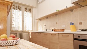 A kitchen with wooden cabinets, a white countertop, a sink, and a dish rack. - Appartamento Anna (San Felice del Benaco)