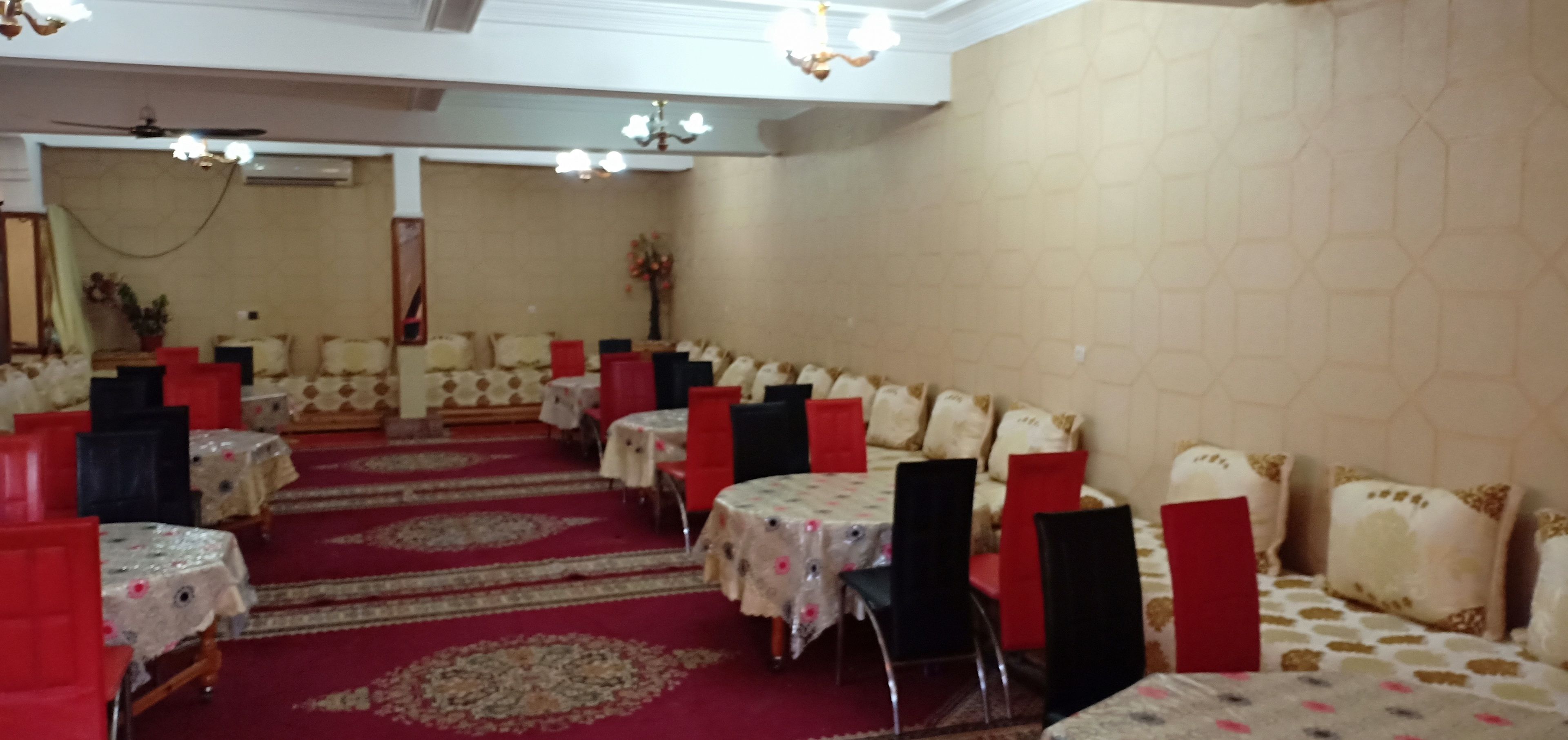 A banquet hall with round tables, red chairs, and a red carpet.