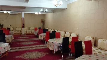 A banquet hall with round tables, red chairs, and a red carpet.