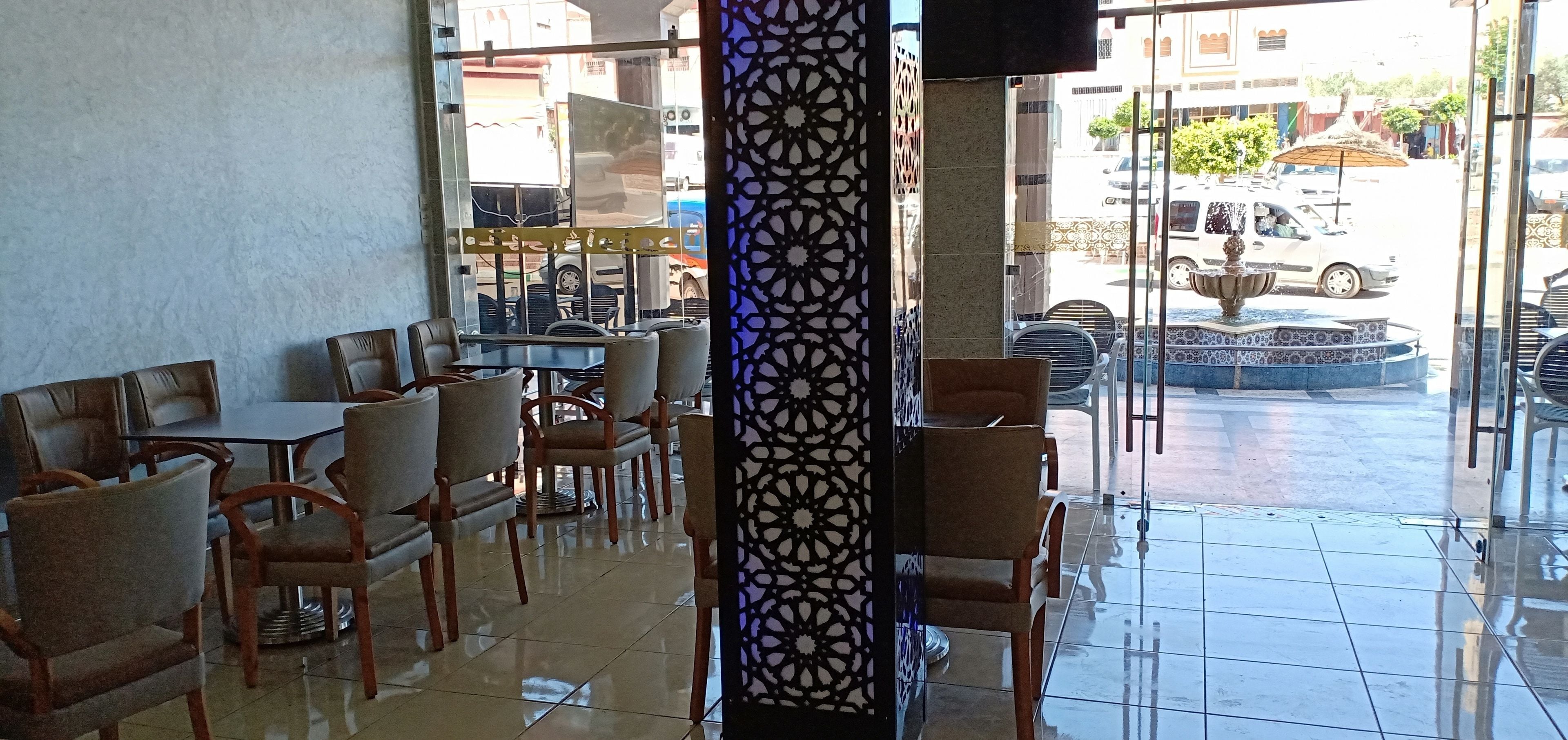 An indoor seating area with tables and chairs, a decorative column, and a view of the street outside.