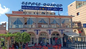 Un edificio de dos pisos con cafetería, restaurante y letrero de hotel.