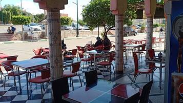 An outdoor café with red chairs and tables, a checkered floor, and a Pepsi advertisement.