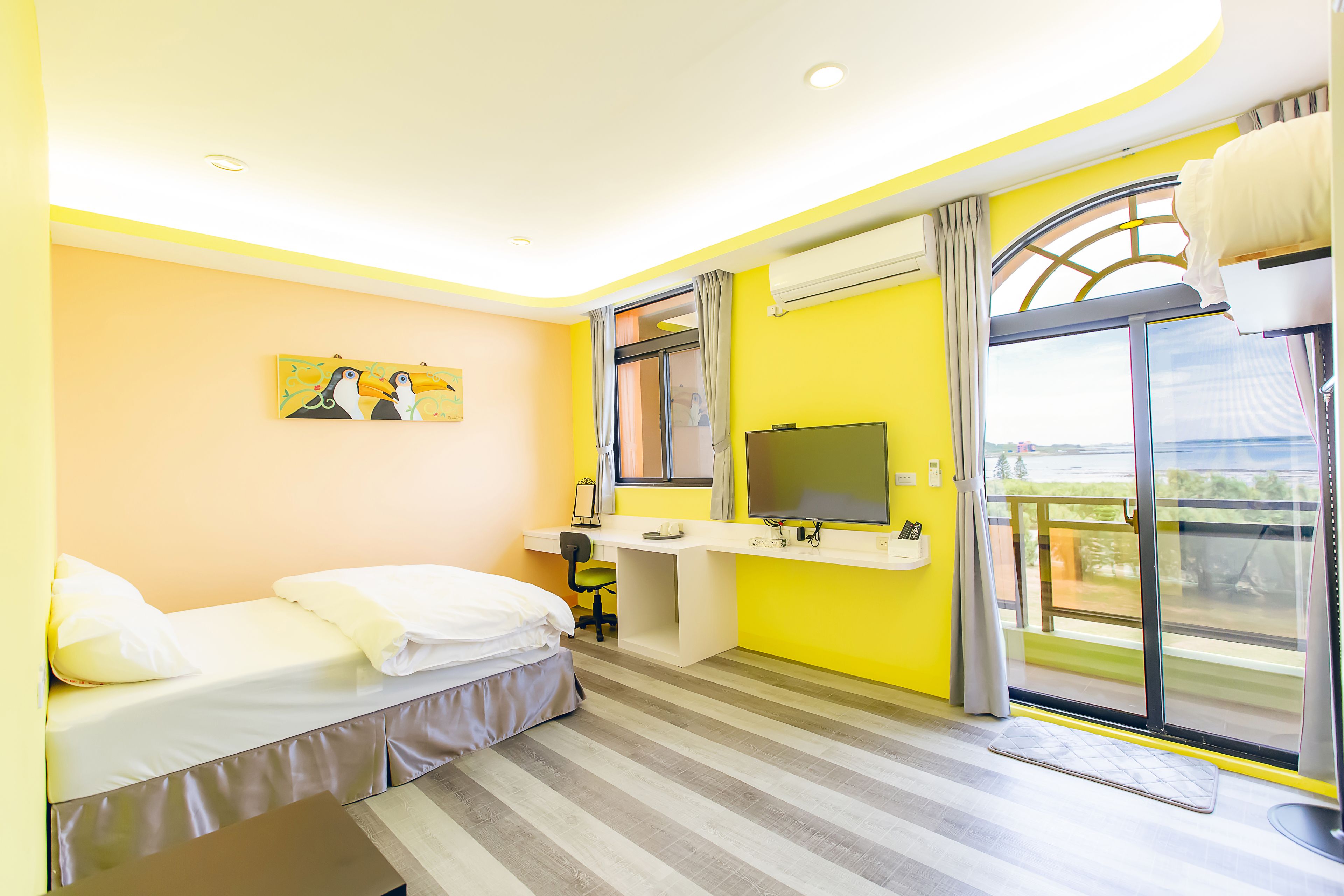 A bright room with a bed, a desk, a TV, and a window with a view.