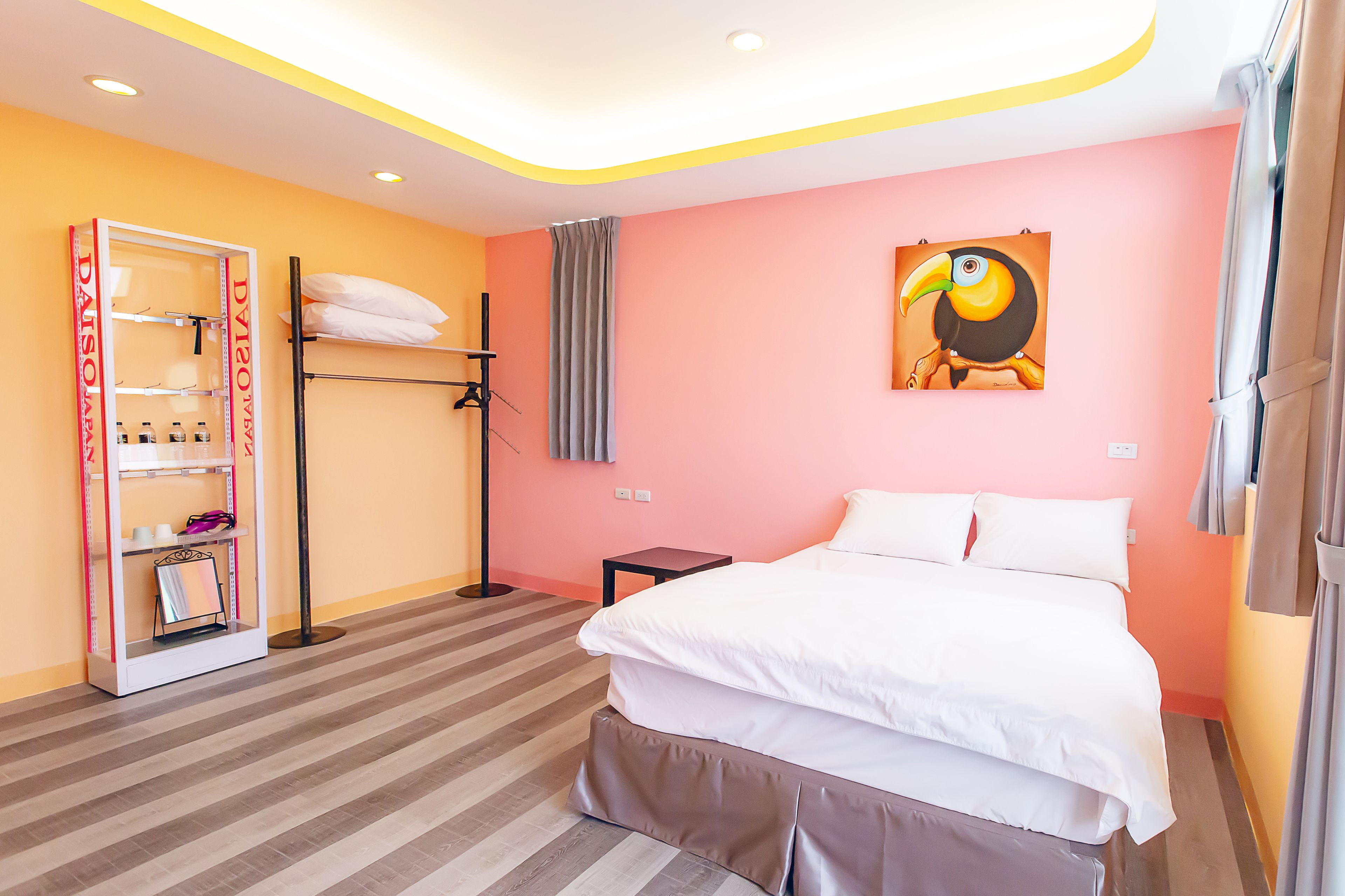 Habitación de hotel con cama, armario, estantería y un cuadro en la pared.